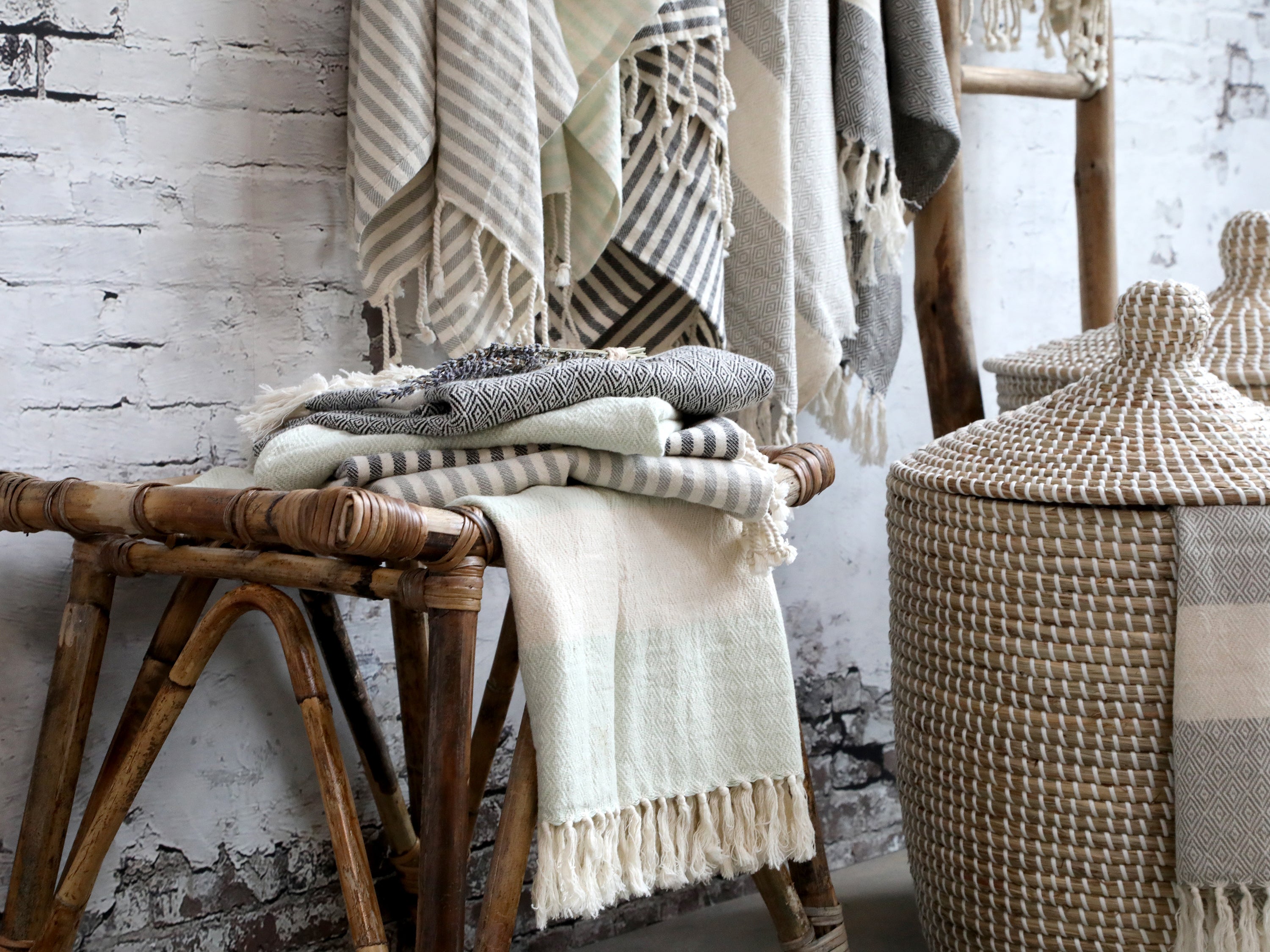 Chic Antique Éternel Handtücher grau weiß aus Baumwolle mit Muster auf Rattanhocker im skandinavischen Badezimmer