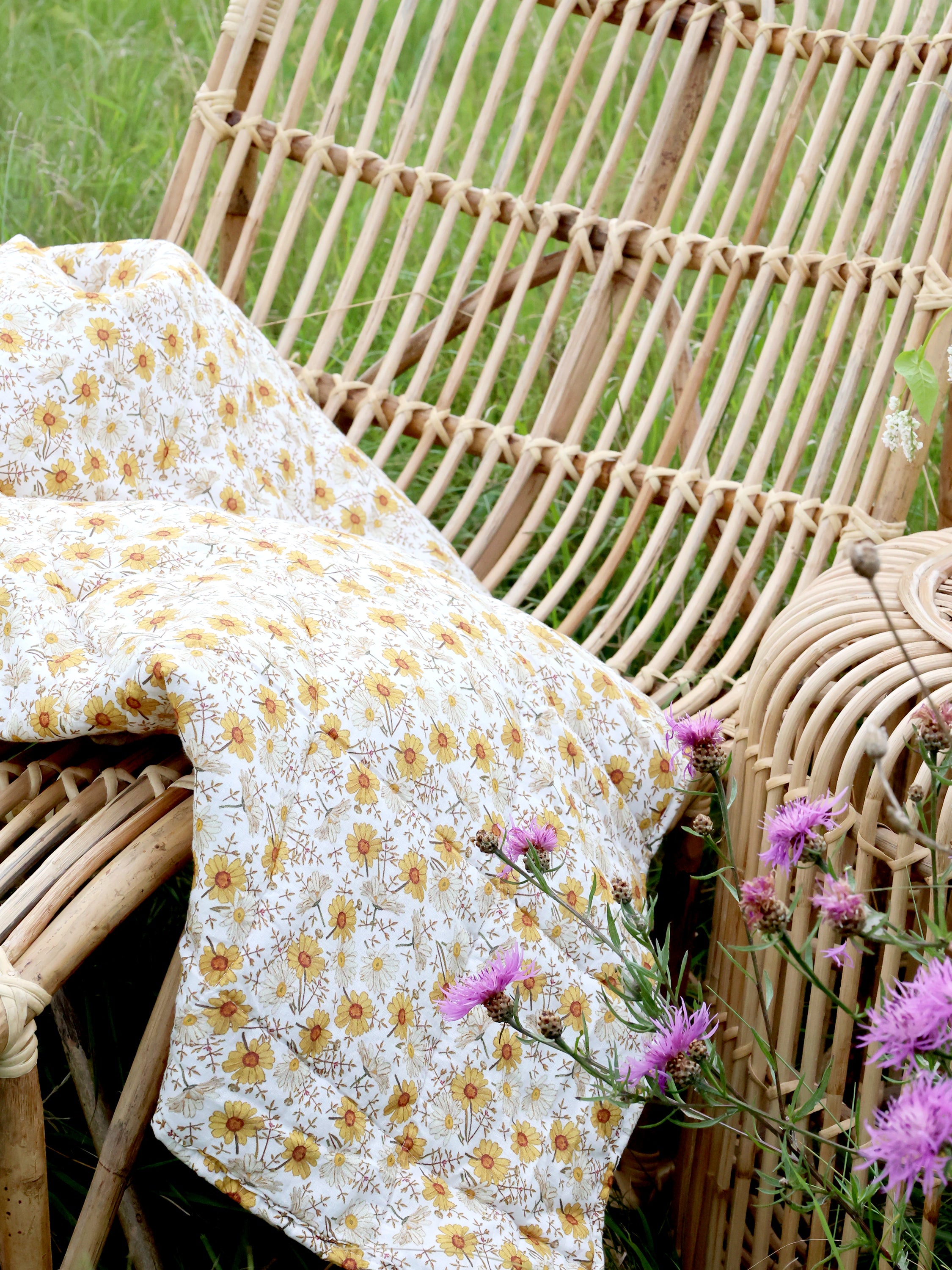 Chic Antique Vintage Quilt mit Margeritenprint auf Rattanstuhl im natürlichen Landhausstil
