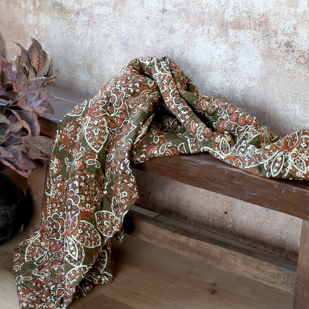 Chic Antique Aix Quilt mit Paisley Muster in Moos und Terracotta dekorativ über einer Holzbank drapiert