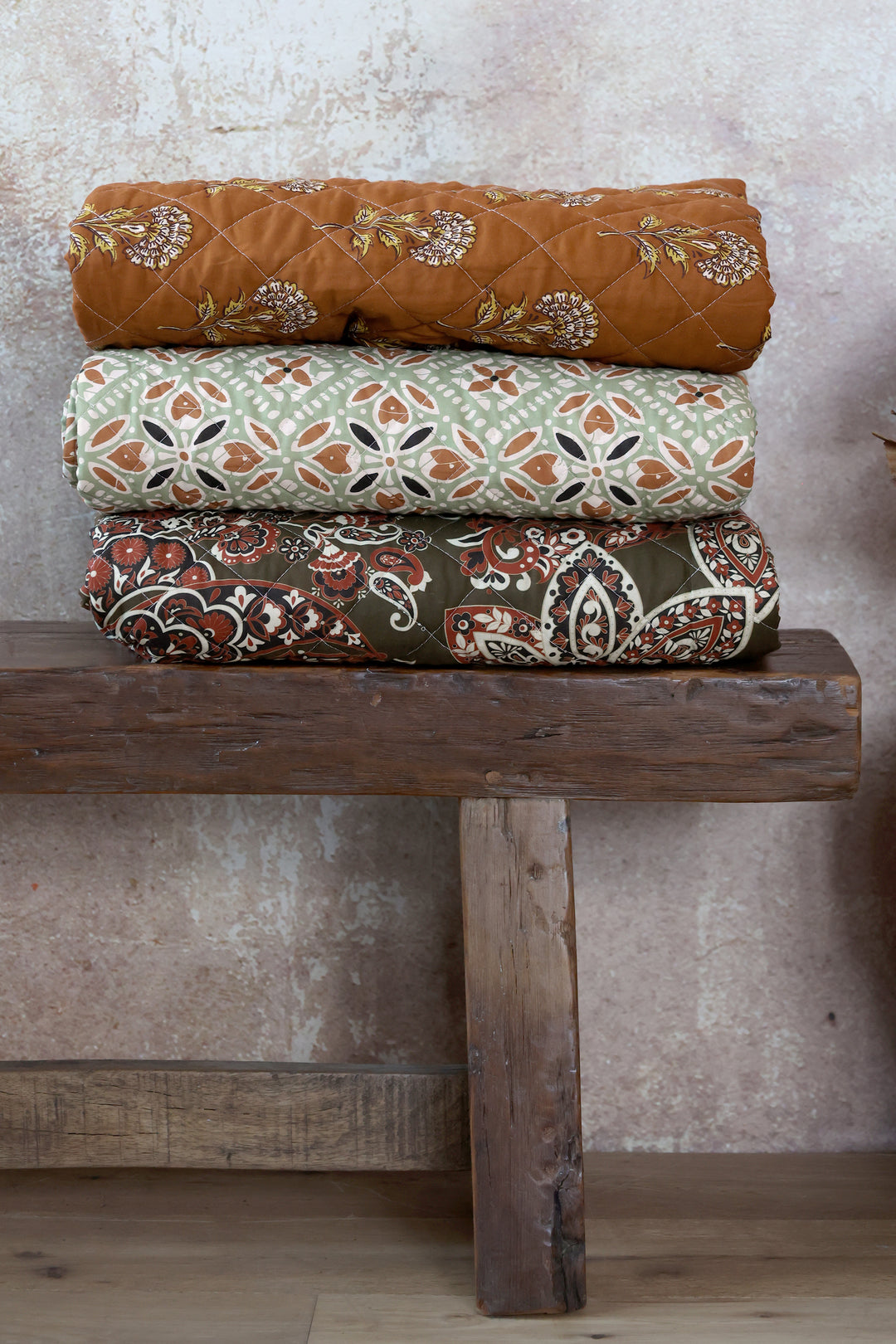 Chic Antique Aix Quilt mit Paisley Motiv in Moos und Terracotta gefaltet auf einer Holzbank im Landhausstil