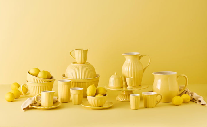 IB Laursen Mynte Geschirr Lemonade in Gelb – Frühstücksteller, Tassen und Schalen im skandinavischen Design vor gelbem Hintergrund