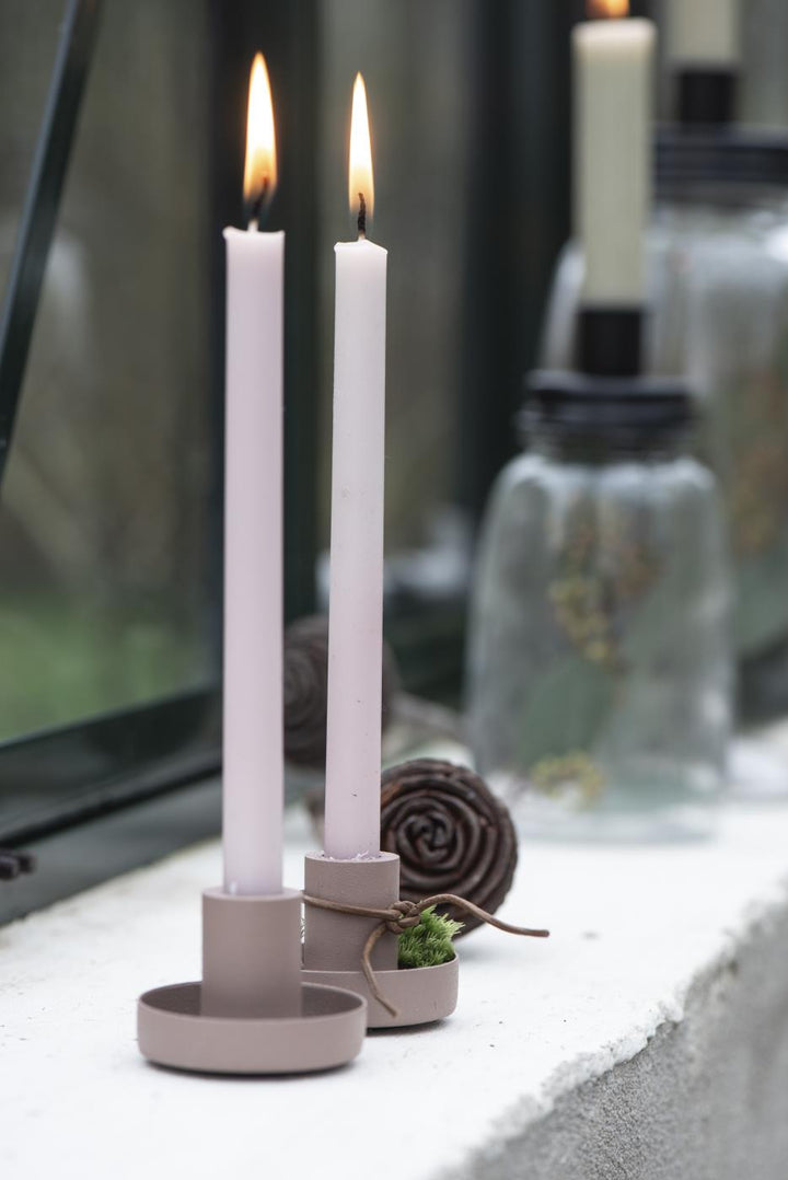 Zwei brennende Ib Laursen Stabkerzen Rosa Malva auf Fensterbank, stilvolle skandinavische Dekoration mit Glasvasen