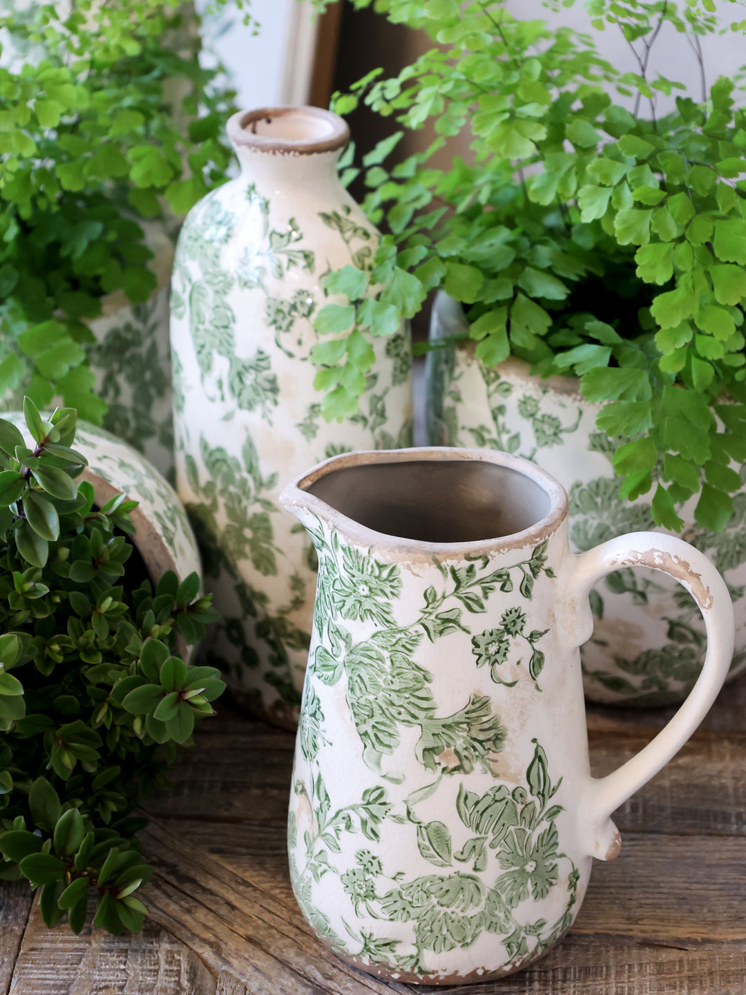 Chic Antique Keramikkanne mit grünem französischem Blumenmuster im Landhausstil als dekorative Vase zwischen Pflanzen