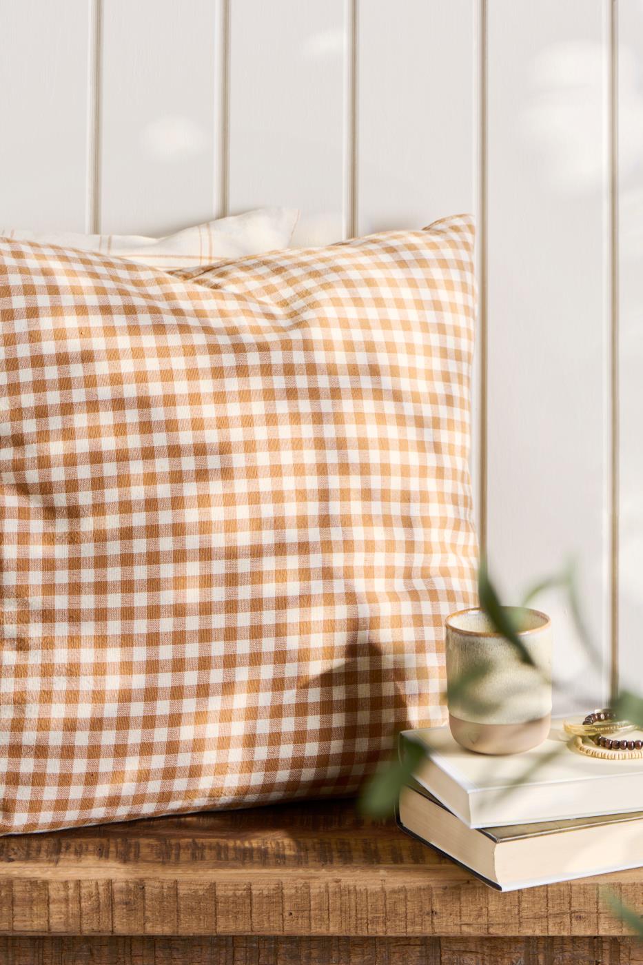 IB Laursen Kissenbezug Luca 50x50 cm in Rustikbraun mit naturfarbenem Karomuster dekoriert auf Holztisch im skandinavischen Wohnstil
