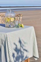 Ib Laursen Tischdecke Viggo hellblau kariert auf Tisch mit Getränkespender und Gläsern am Strand