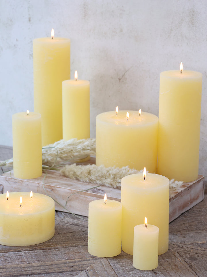 Macon Stumpenkerzen von Chic Antique in Honigmelone dekoriert auf Holztablett mit Trockenblumen und warmem Kerzenlicht