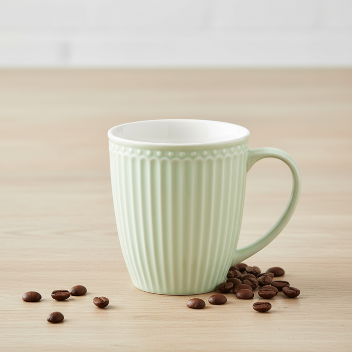 GreenGate Tasse Alice Hellgrün 0,35 l aus Porzellan mit Rillenstruktur neben Kaffeebohnen