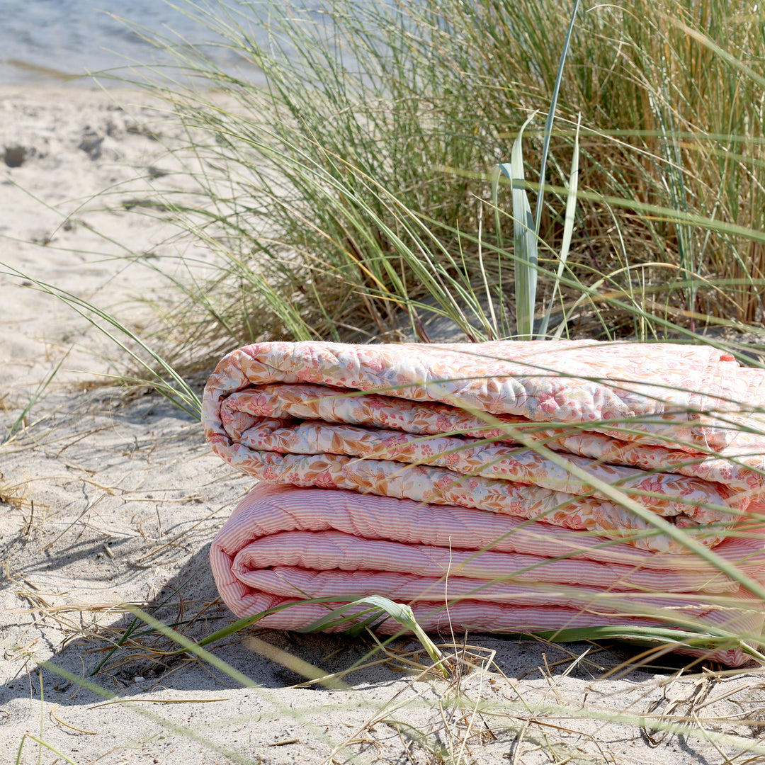 Zusammengelegter Chic Antique Aix Quilt mit Blumenmuster in Rosa und Sky Blue am Strand im skandinavischen Stil