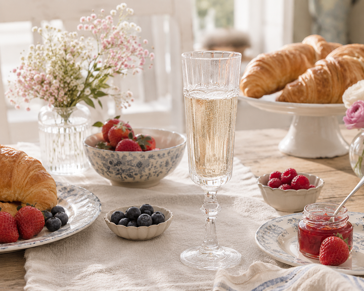 Chic Antique Antoinette Champagnerglas mit Perlenkante auf hellem skandinavischem Brunch Tisch mit Croissants und Beeren