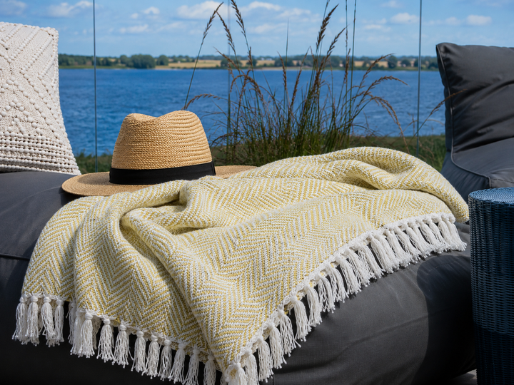 Alttext: Olivgrünes Chic Antique Plaid auf gemütlicher Terrasse am Wasser im skandinavischen Stil
