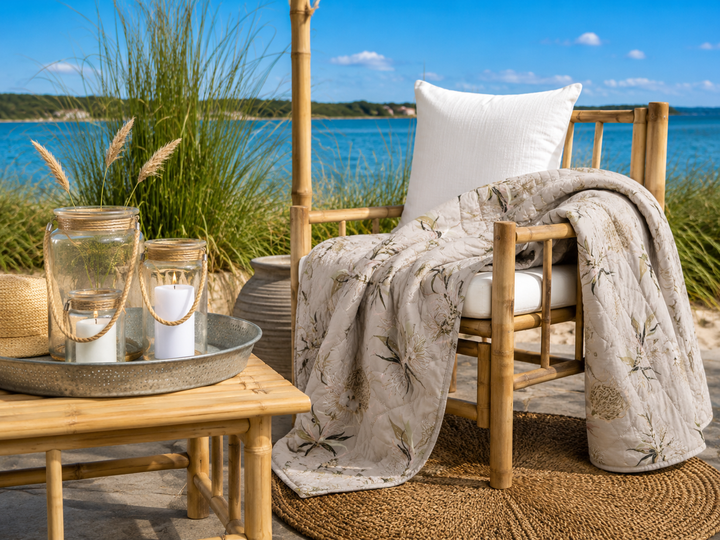 Beigefarbener Quilt mit floralem Muster im natürlichen Boho Stil am Wasser