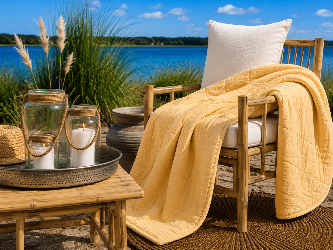 Alttext: Gelber Quilt im sommerlichen Boho Landhausstil auf Terrasse am blauen See