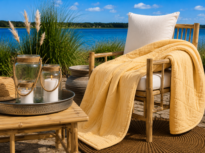 Alttext: Gelber Quilt im sommerlichen Boho Landhausstil auf Terrasse am blauen See