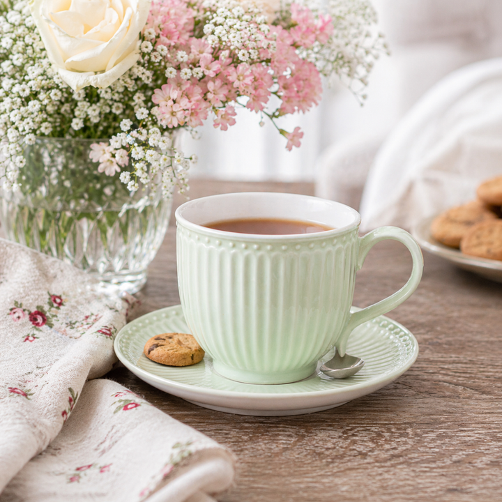 GreenGate Tasse mit Untertasse Alice hellgrün in Nutzung mit Tee auf Holztisch im skandinavischen Landhausstil