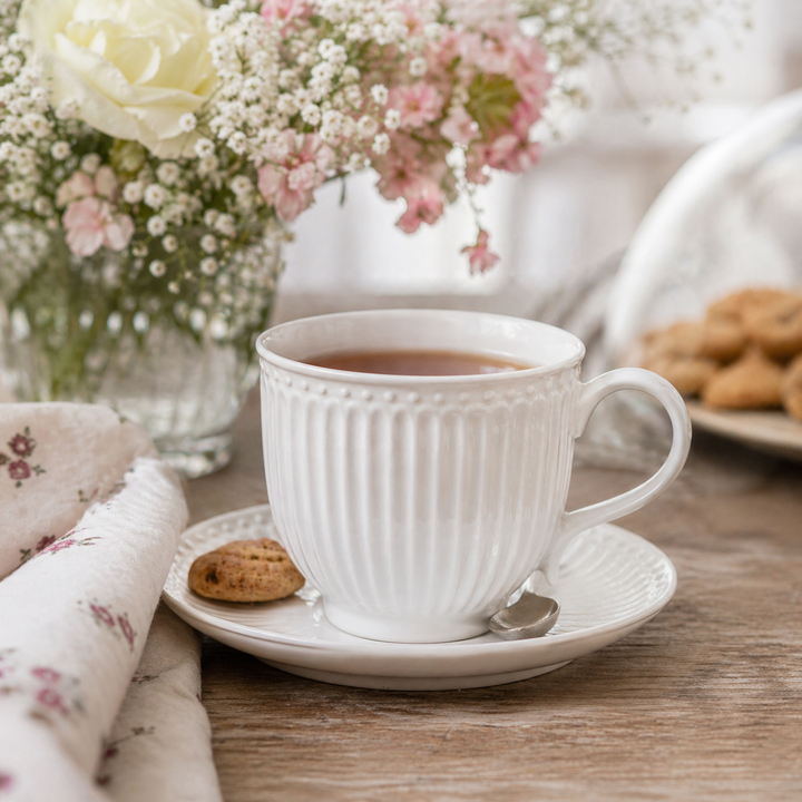 GreenGate Tasse mit Untertasse Alice weiß in Nutzung mit Tee auf Holztisch im skandinavischen Landhausstil