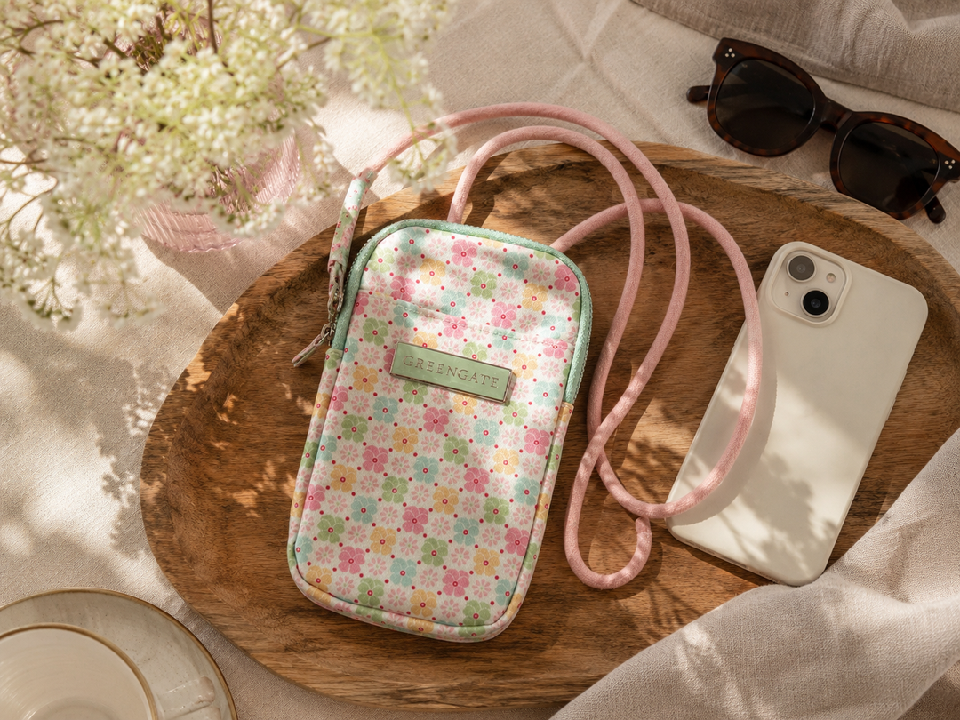 GreenGate Handybag mit floralem Pastellmuster auf Holztablett mit Smartphone und Sonnenbrille im natürlichen Hygge Stil