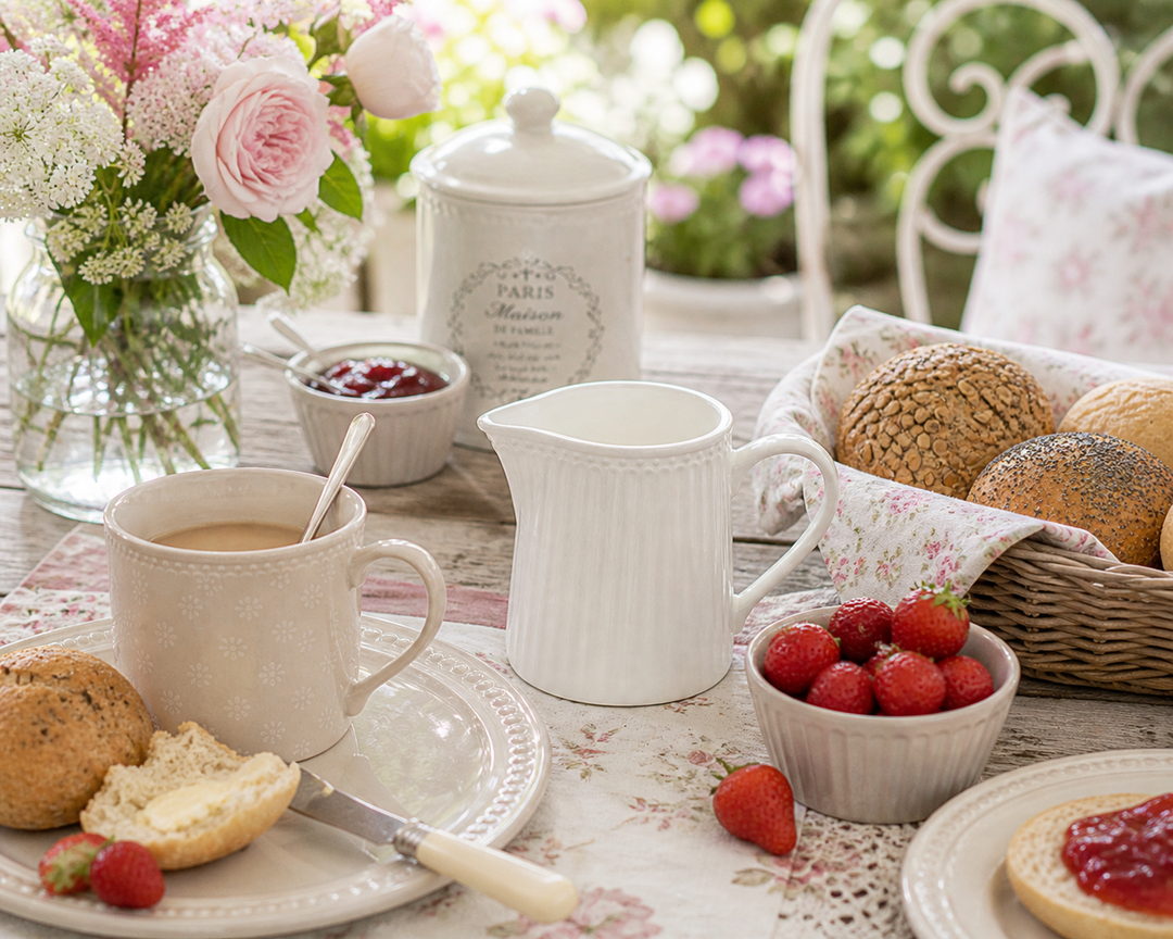 GreenGate Milchkännchen Alice Weiß auf sommerlicher Terrasse im Shabby Chic Stil mit Erdbeeren, Brötchen und Geschirr