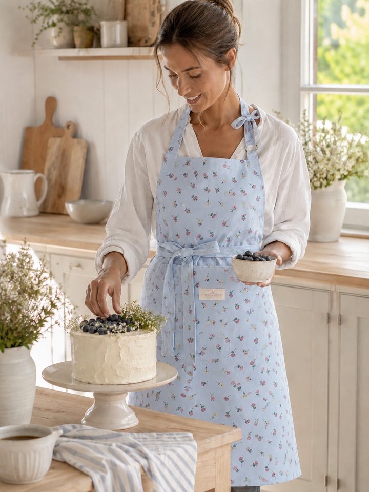 GreenGate Schürze Hellblau mit floralem Muster getragen in heller skandinavischer Landhausküche beim Backen