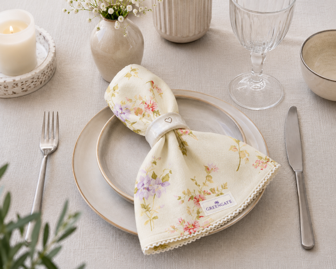 GreenGate Stoffserviette mit floralem Blumenmuster in Creme auf gedecktem Landhaus Tisch mit Kerze und Keramik