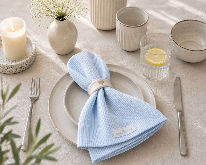 GreenGate Stoffserviette Alicia hellblau mit Serviettenring auf natürlichem Tischarrangement im Hygge Stil