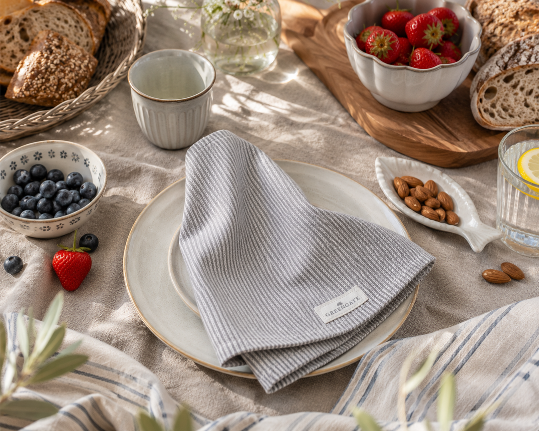 GreenGate Stoffserviette Alicia hellgrau in gemütlicher Frühstücksszene mit Brot, Beeren und heller Keramik