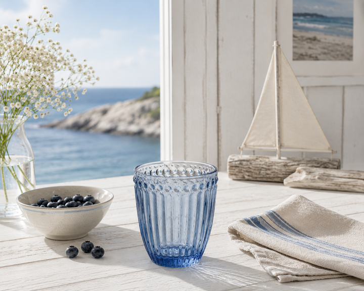 GreenGate Wasserglas Alice Blau in heller skandinavischer Küstenküche mit maritimer Dekoration und Meerblick