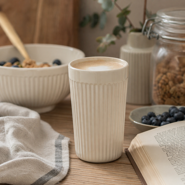 IB Laursen Mynte Café Latte Becher Butter Cream in gemütlicher Hygge Stimmung mit Kaffee, Kerze und skandinavischer Dekoration auf Holztisch
