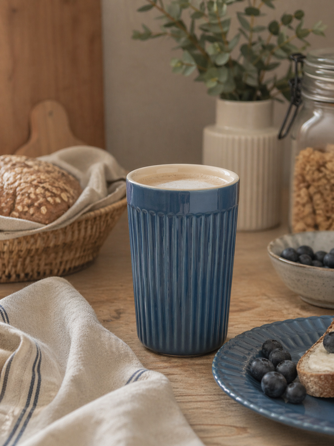 IB Laursen Mynte Café Latte Becher Cornflower in Nutzung als Kaffeebecher in skandinavischer Küchenszene mit Frühstück und natürlicher Dekoration