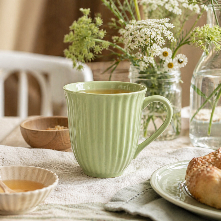 IB Laursen Mynte Tasse Wasabi in Nutzung mit Tee auf gedecktem Tisch im skandinavischen Landhausstil